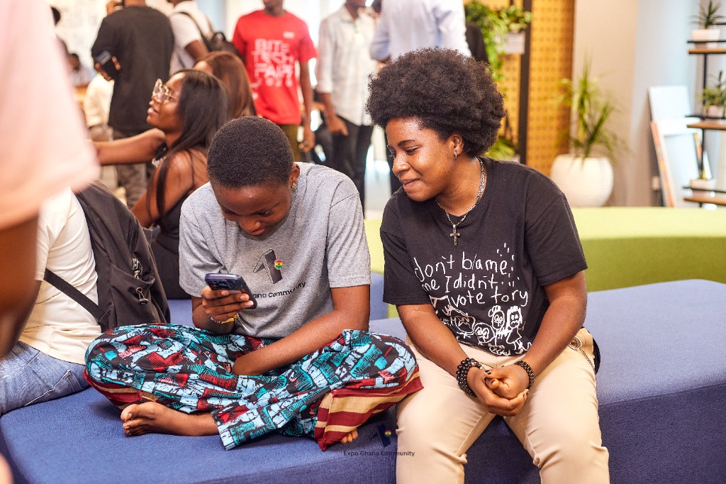 Two community members sharing something on a phone during a break at the hackathon